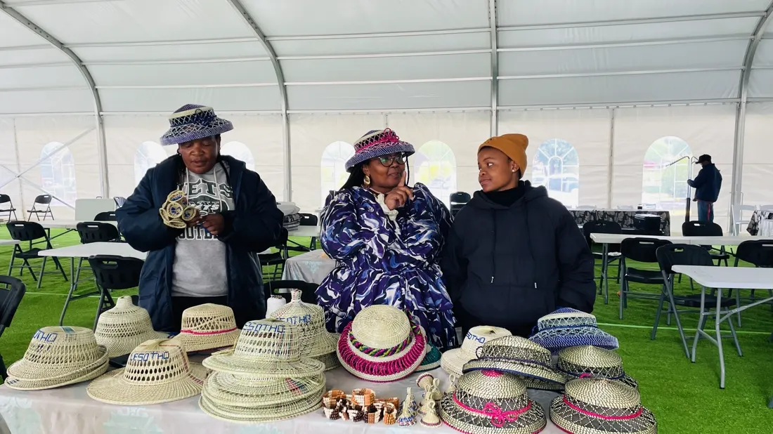 Delegates inside the exhibition marquee with woven hats displayed along the tables
